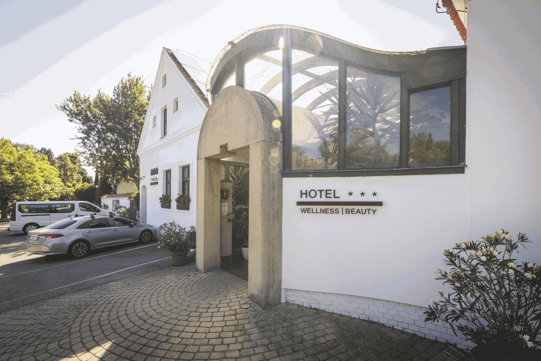 A Tornácos hotel boltíves bejárata és a Hotel Wellness Beauty felirat napfényben