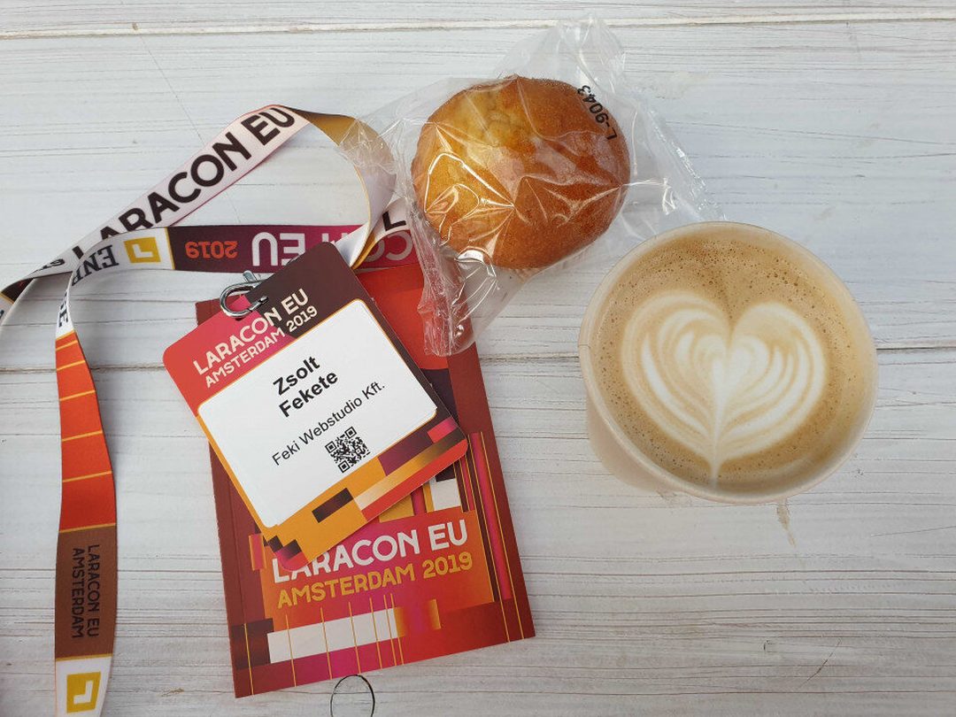 Laracon EU Amsterdam 2019 belépőkártya és nyakpánt Zsolt Fekete névvel, mellette muffin és cappuccino