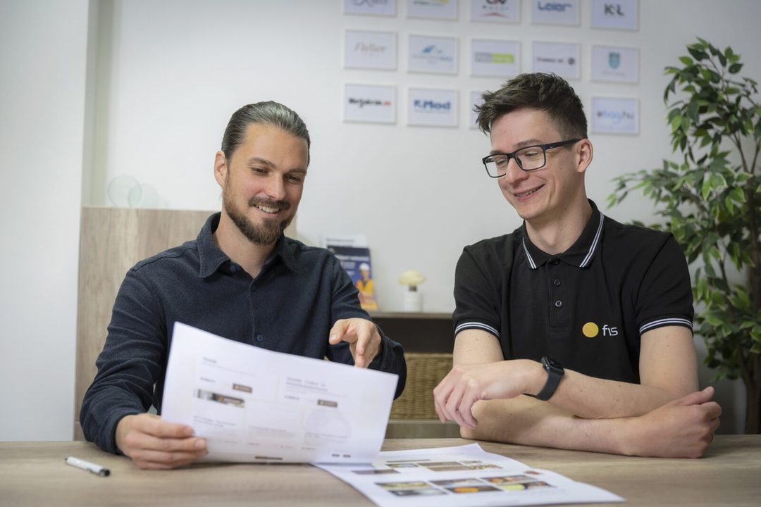 Két fws kolléga egy nyomtatott weboldaltervet néz át az irodában