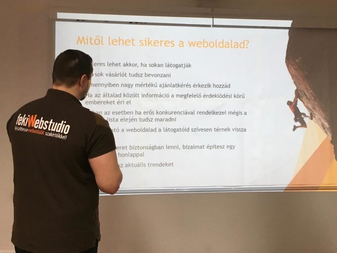 Feki Webstudio pólós előadó a kivetített „Mitől lehet sikeres a weboldalad?” című dia előtt