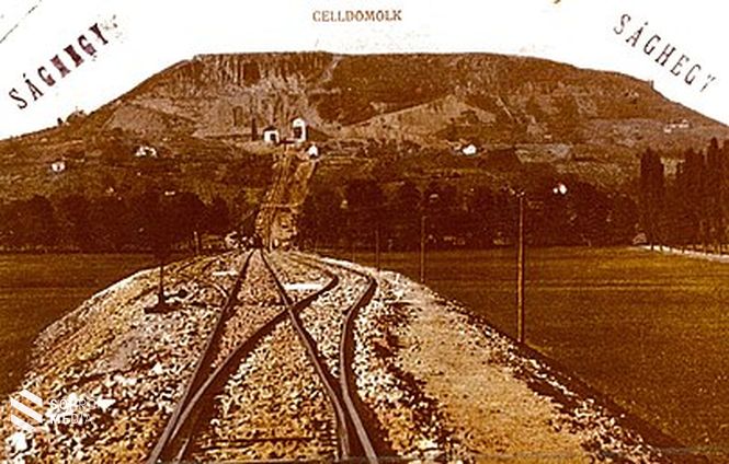 A Ság hegy, Eötvös 1891-es méréseinek helyszíne. A hegy eredetileg a Badacsonyhoz hasonlított, de különösen szabályos csonka kúp alakú bazaltsapkával. Így könnyen kiszámítható volt az ingára gyakorolt várható hatás (képeslap 1911-12-ből, a bazaltbánya megnyitása után) 